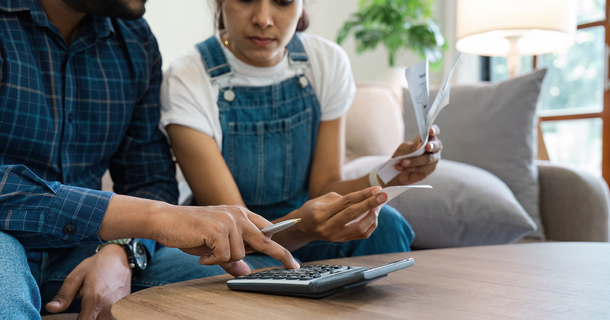 two people sitting on the couch looking over some papers.